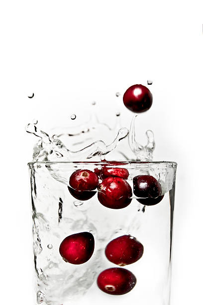 Cranberries splashing in a glass of water. stock photo