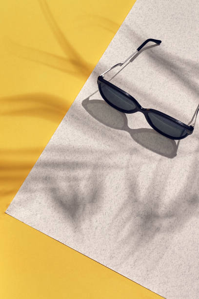 istock Stylish sunglasses with bright sunlight and shadow from palm leaves 951214056