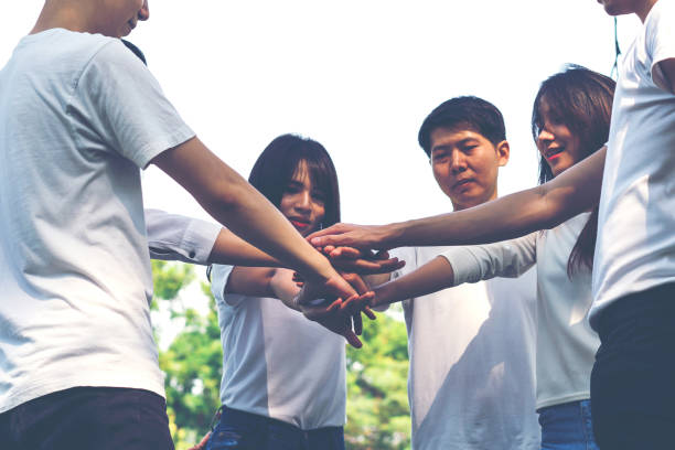 istock Young people putting hands together. Friends with stack of hands showing unity and teamwork. 951218356