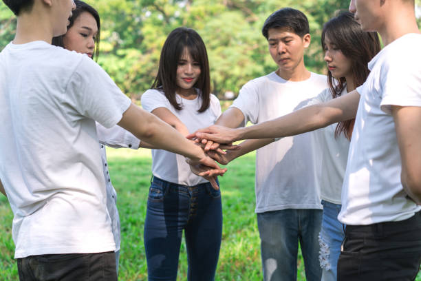 istock Young people putting hands together. Friends with stack of hands showing unity and teamwork. 951218420