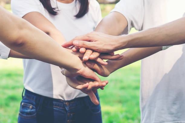 istock Young people putting hands together. Friends with stack of hands showing unity and teamwork. 951218502