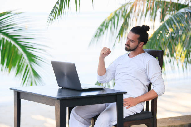 istock Man relaxing on the beach with laptop, freelancer show win 951246308