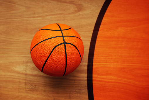 Basketball ball laying on hardwood court floor, top view