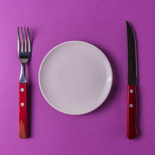 istock Still life of white empty plate with cutlery on colored background. 951254820
