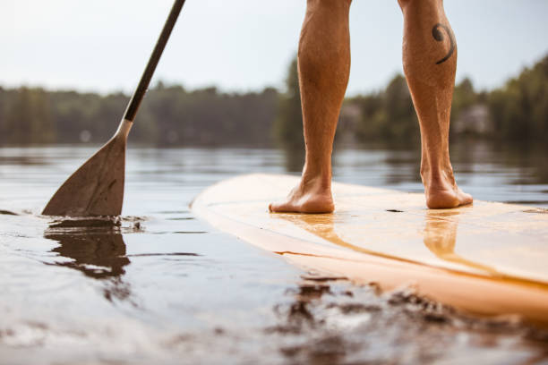 istock SUP Stand-up Paddleboard. Close-up on legs of a man paddleboarding 951269958