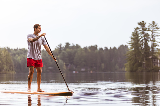 istock Un hombre es paddle y Remo en un lago. SUP stand-up Paddleboard. Mauricie, Quebec, Canadá 951270118