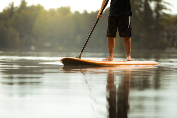SUP Stand-up Paddleboard. Close-up on legs of a man paddleboarding stock photo