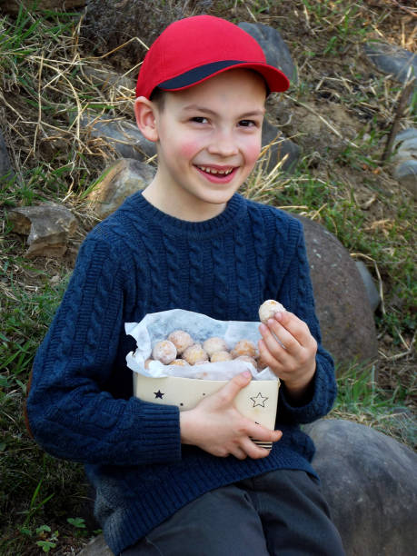 istock Happy boy in red cap is eating doughnut. Oat donuts with cinnamon, powdered sugar and coffee. Round fritter. Sweet tasty food for kids. Space for text 951270758
