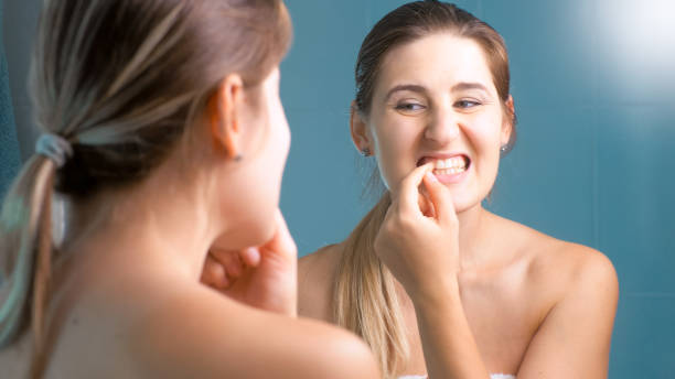 Portrait of young brunette woman trying to take out food stuck in teeth Portrait of brunette woman trying to take out food stuck in teeth tooth in hand stock pictures, royalty-free photos & images