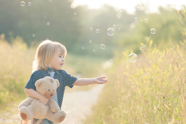 istock Little boy playing with soap bubbles and bear toy 951283274