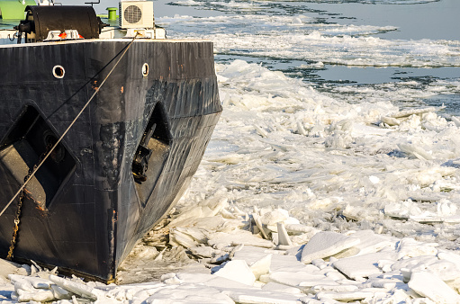 Small boat or ship stuck in ice of frozen river in the winter season