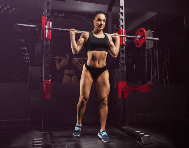 istock Charming girl in a gym performs an exercise with a barbell. 951294624