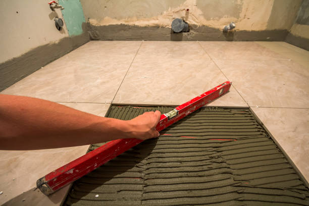 istock Ceramic tiles and tools for tiler. Worker hand installing floor tiles. Home improvement, renovation - ceramic tile floor adhesive, mortar, level. 951299544