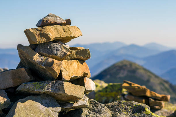 istock Stack of stones covered with moss on top of a mountain on mountains background. Concept of balance and harmony. Stack of zen rocks. Wild nature and geology detail. 951299892