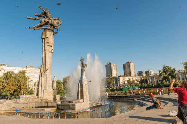 Manas Statue in fountain with urban background Manas Statue at the fountain, people taking photography and urban background on sunny day. Clear blue sky and some birds in the air. Bishkek, Kyrgyzstan bishkek photos stock pictures, royalty-free photos & images