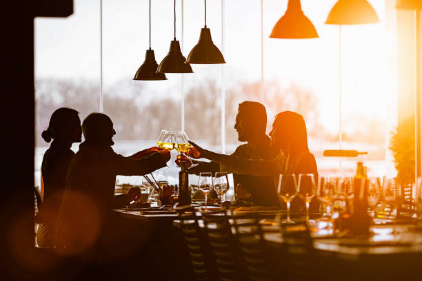 Slhouette of a Group of Friends Toasting During Lunch Time in a High-End Restaurant stock photo