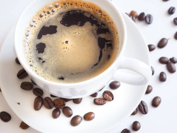 istock coffee with a white cup and brown beans on a saucer 951305484