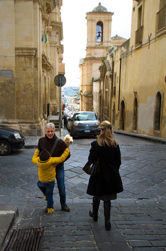 Noto, Sicily: A boy with a Barbie doll hugs his father on a street in downtown Noto, a UNESCO World Heritage site in Siracusa Province.