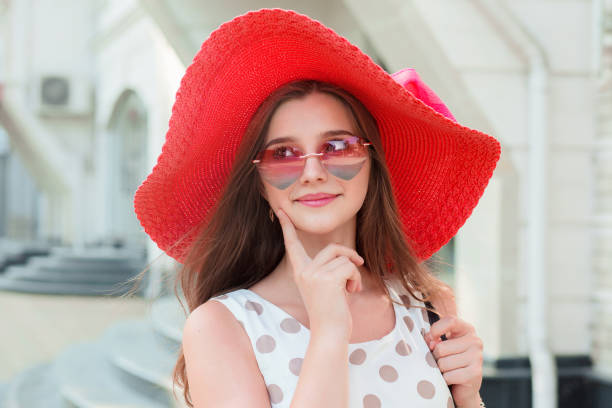 teen fille avec coeur longue brune chapeau rose en forme de lunettes de soleil à la recherche de suite souriant - h shaped photos et images de collection