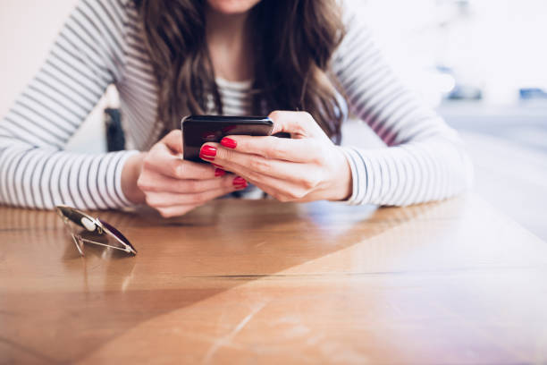 istock Young woman drinking red wine at restaurant, using smart phone 951345278