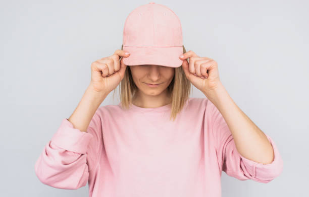 closeup retrato de rubia caucásica joven femenina con cubierta y un suéter de color rosa ojos con tapa rosa, proteger de los rayos del sol, aislados en fondo blanco de estudio. concepto de emoción de personas positivas - pink hat fotografías e imágenes de stock