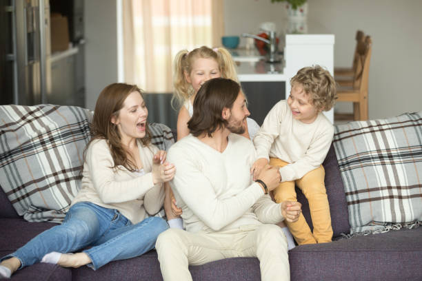 istock Kids and parents laughing having fun playing sitting on sofa 951349822
