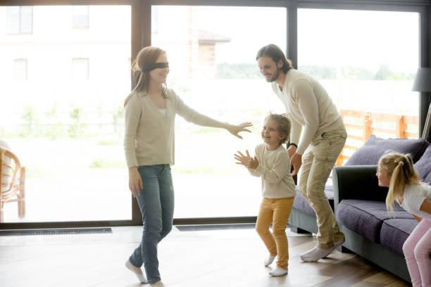 istock Family kids playing hide and seek game with blindfolded mom 951349890