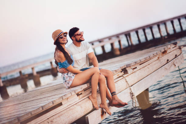 istock Young hipster couple sitting on jetty looking at sunset 951355906