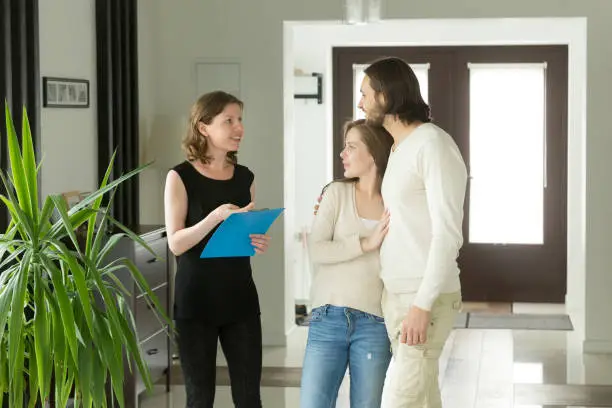 Photo of Real Estate Agent or landlord showing modern luxury house to couple customers