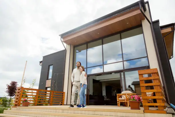 Photo of Happy young couple embracing standing on luxury house front porch