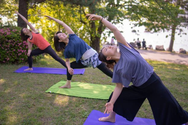 istock Three women practicing yoga in green field 951366882