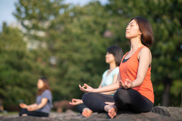 Three woman practicing yoga on rocks