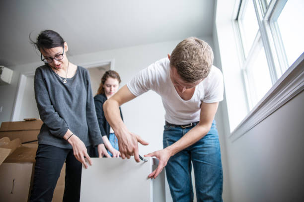 the family moving in to the new apartment. the young 30 years old man and two teenage girls, sisters, unboxing and assembling furniture. - independence lifestyles smiling years imagens e fotografias de stock