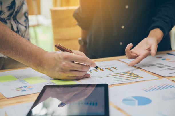 istock Startup Concept.Young businessman discussing documents and ideas at home office. Young businessmen are pointing at graphs while friends are explaining summary results. 951431594