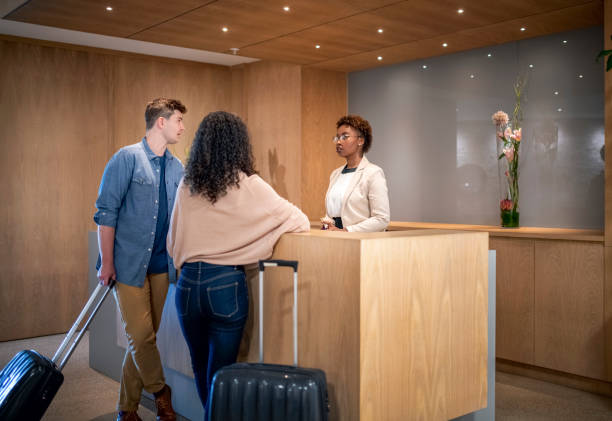 istock Couple with luggage talking to receptionist 951445200