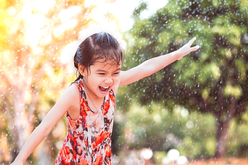 Happy asian little child girl having fun to play water in summer time with fun