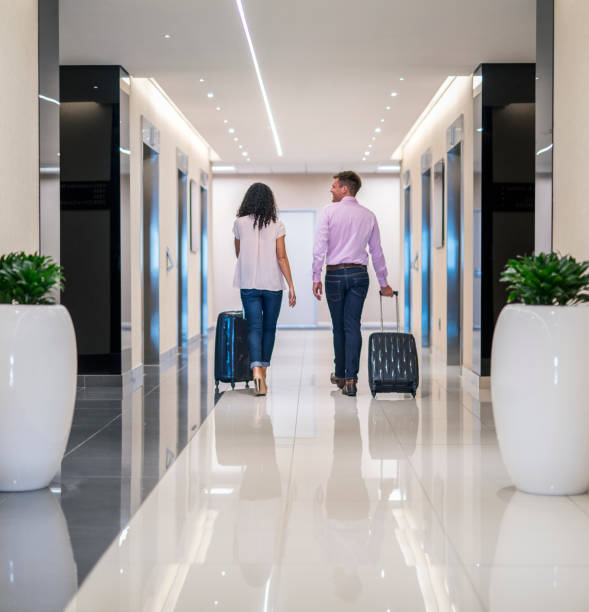 istock Couple walking with luggage in hotel corridor 951447700