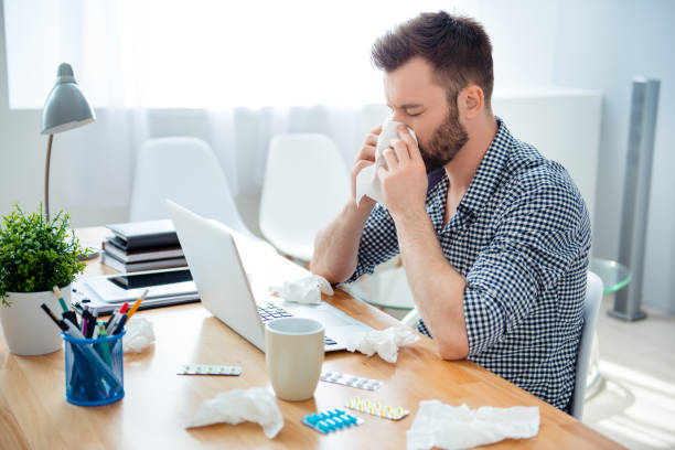 istock businessman having cold in the head and sitting at workplace 951450564