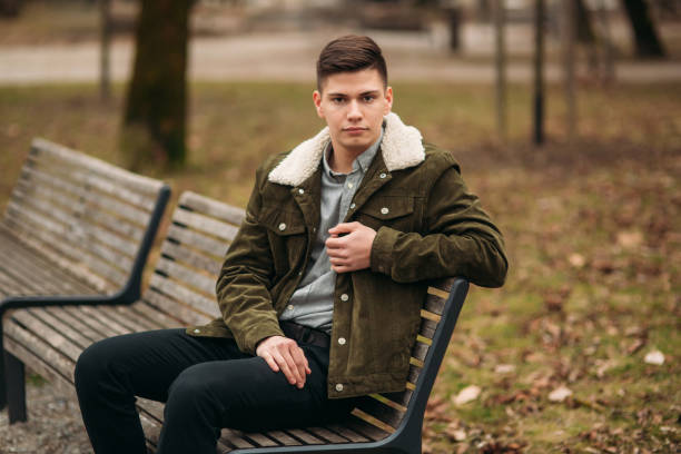 istock Nice guy sitting on the bench outdoors in cloudy weather 951451534