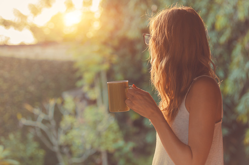 Cute girl enjoying morning coffee on the porch.
