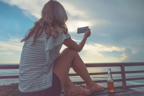 istock Girl using cellphone on the ocean shore. 951452390