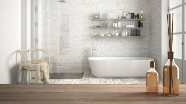 istock Wooden table top or shelf with aromatic sticks bottles over blurred classic bathroom with bathtub, white architecture interior design 951455112