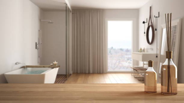 istock Wooden table top or shelf with aromatic sticks bottles over blurred modern bathroom with shower and bathtub, white architecture interior design 951455266
