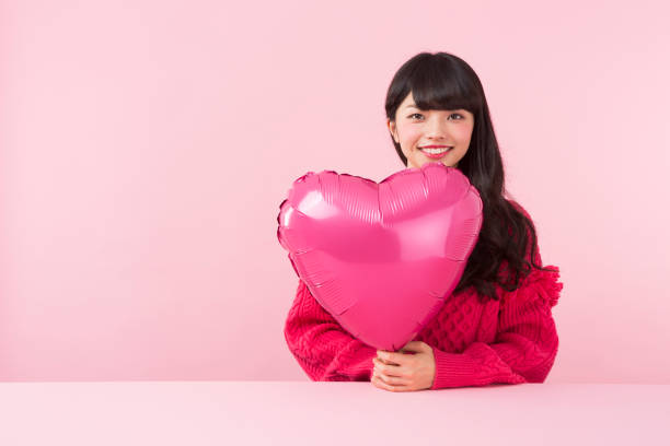 istock A young woman holding a heart shaped balloon 951477494