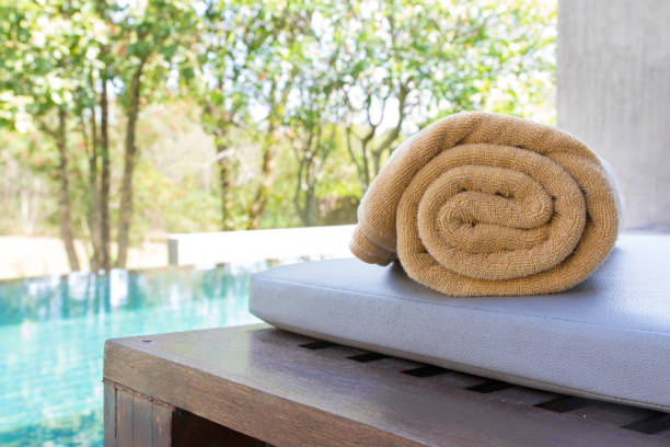 istock Rolled orange towel placed on the bed beside the pool 951477690