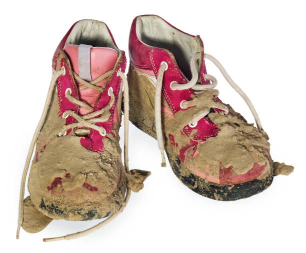 Children's tiny shoes covered with mud. Dirty leggings for children's feet in raspberry. Children's tiny shoes covered with mud. Dirty leggings for children's feet in raspberry and white color isolated on a white background. kids dirty shoes stock pictures, royalty-free photos & images