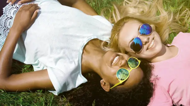Pretty multiracial girls lying on grass, smiling, enjoying holidays, friendship