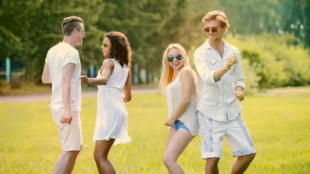 Two cute couples hanging out at open-air festival, dancing to music, having fun