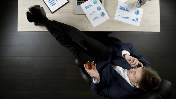 istock Successful investor viewing project report, talking over phone, drinking cognac 951481218