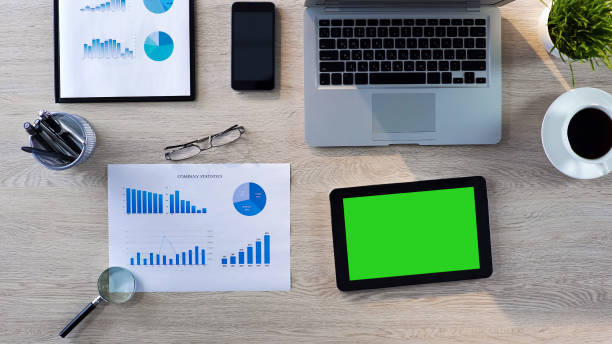 istock Top view of office workplace, tablet with green screen lying on the table, app 951481222